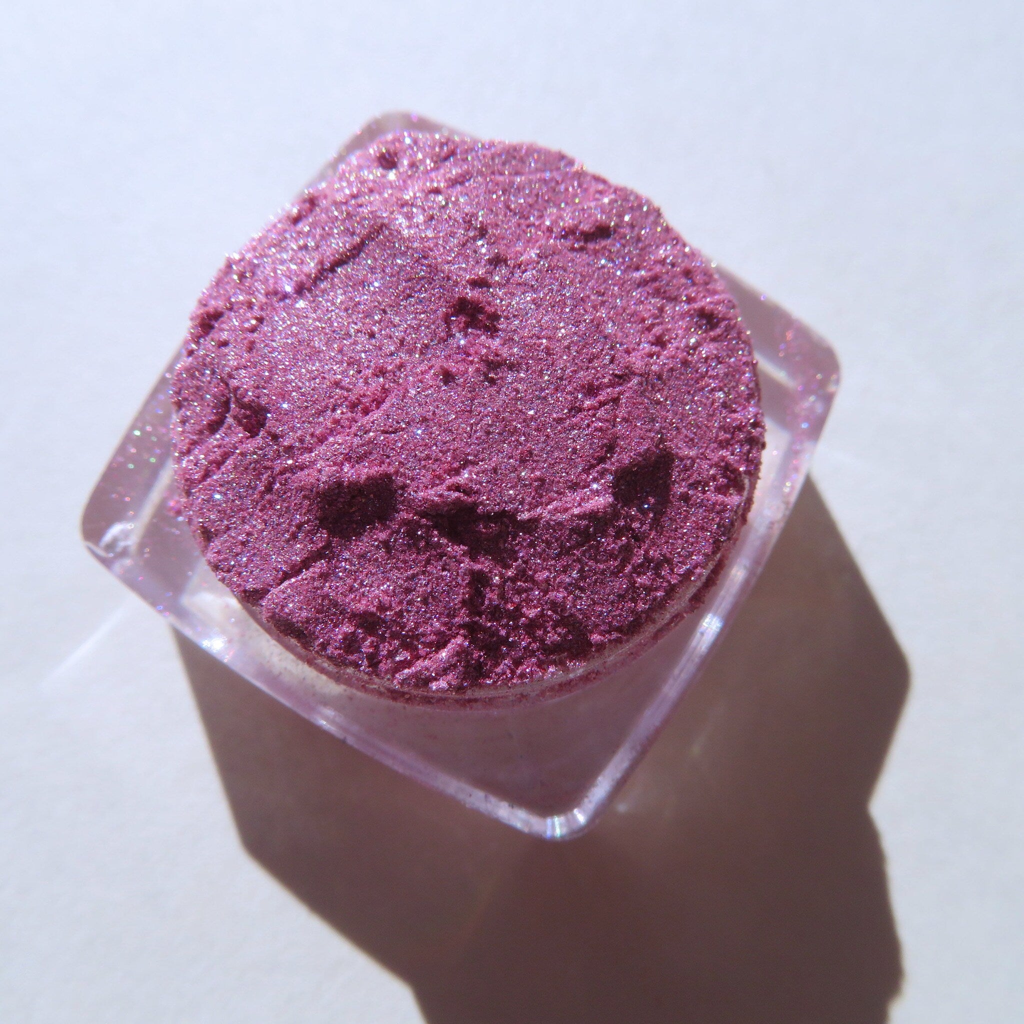 Open compact showing loose shimmery red-pink vegan mineral eye shadow with candy cane design