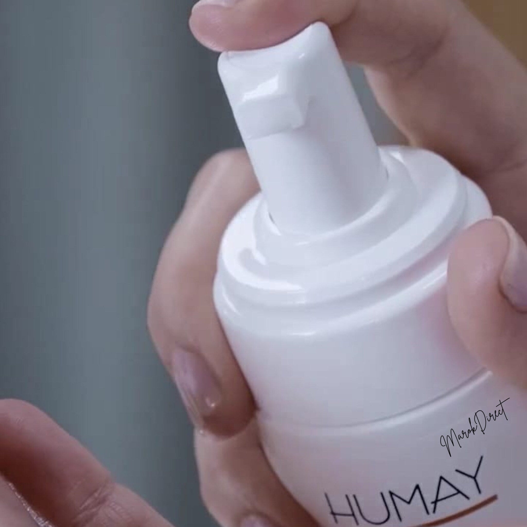 White pump bottle with white cap being pressed by hand, HUMAY text visible