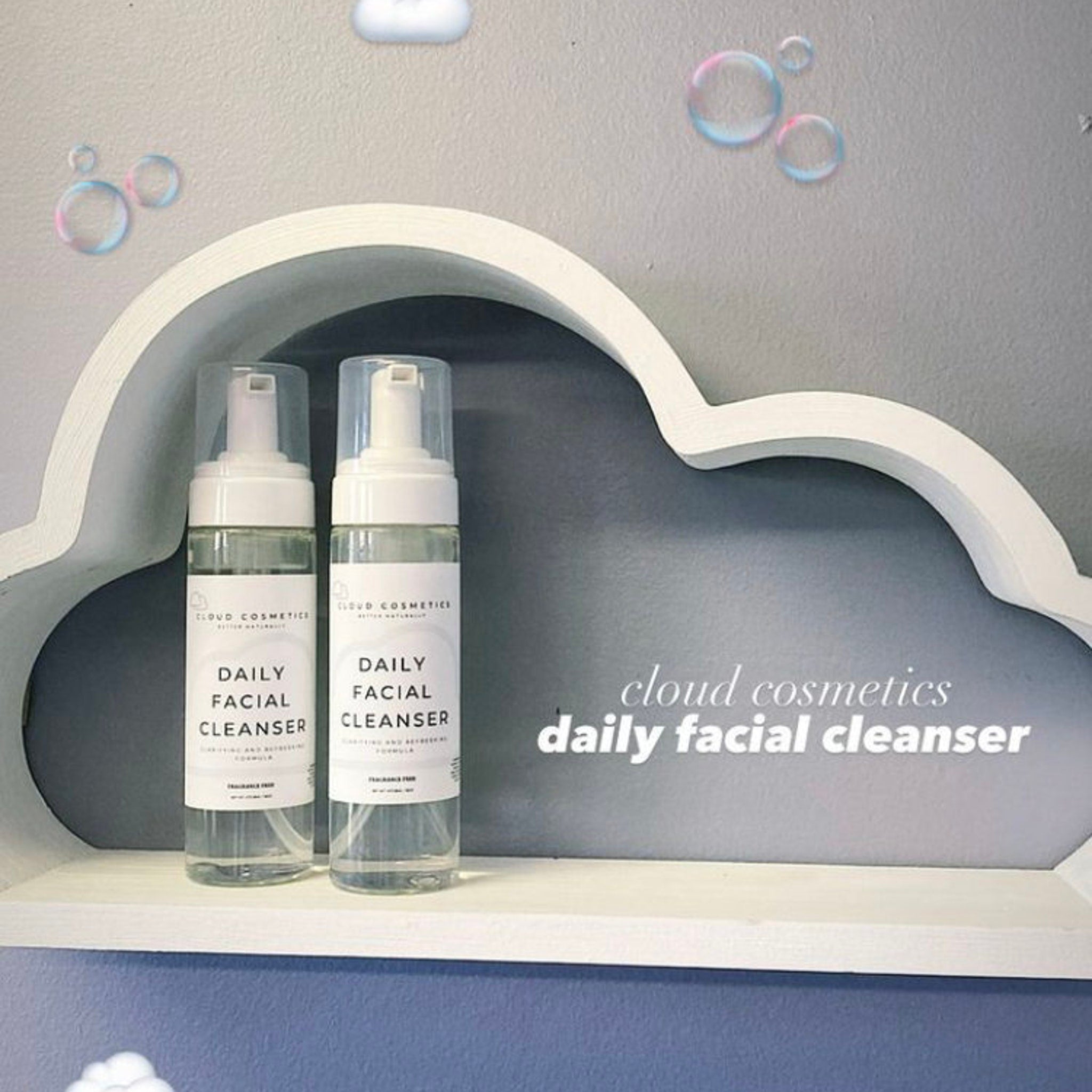 Daily facial cleanser bottles with white labels, clear liquid, and white pump tops displayed on a cloud shelf, Cloud Cosmetics