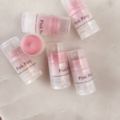 Lip balm tubes with pink tinted balm, clear plastic casing, and Pink Posy text on label