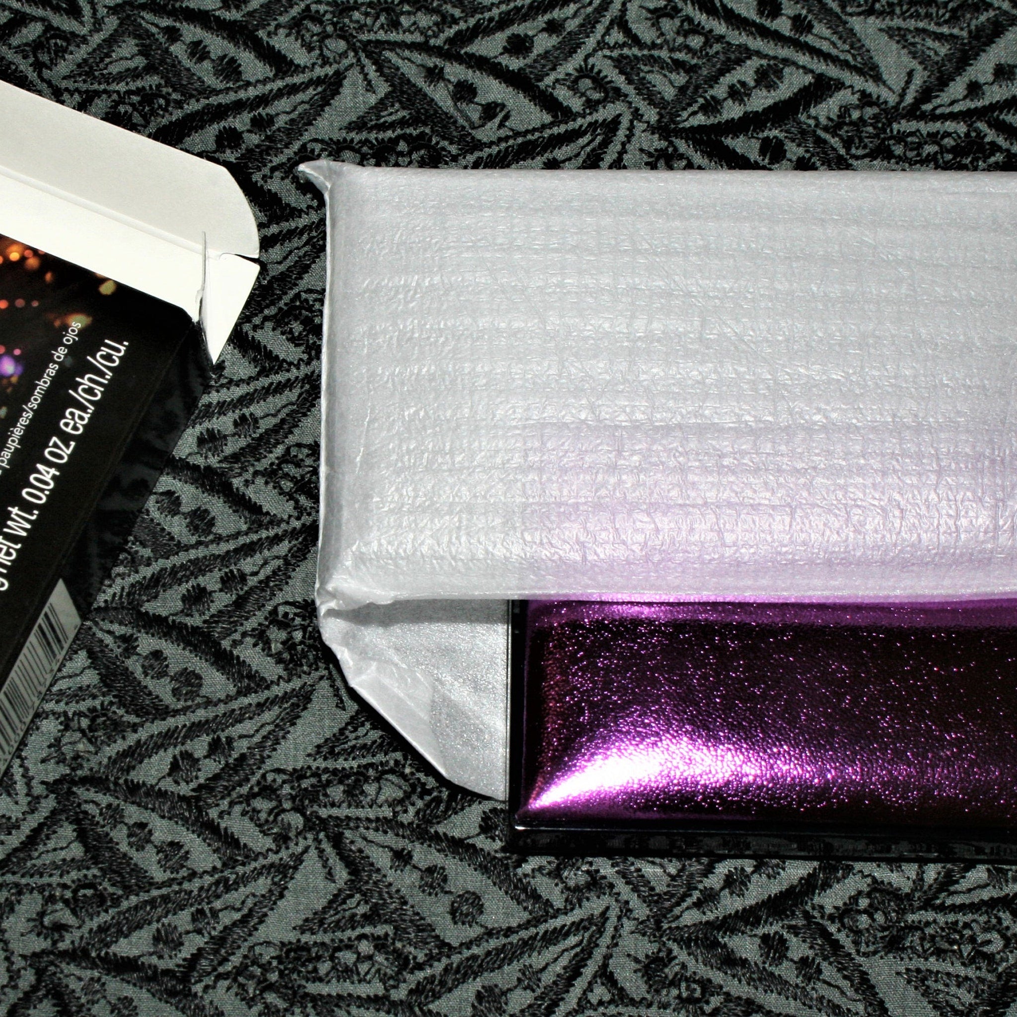 Close-up of Vintage Avon Luxe Clutch eyeshadow compact showing shimmering bronze and plum shades in rectangular pans