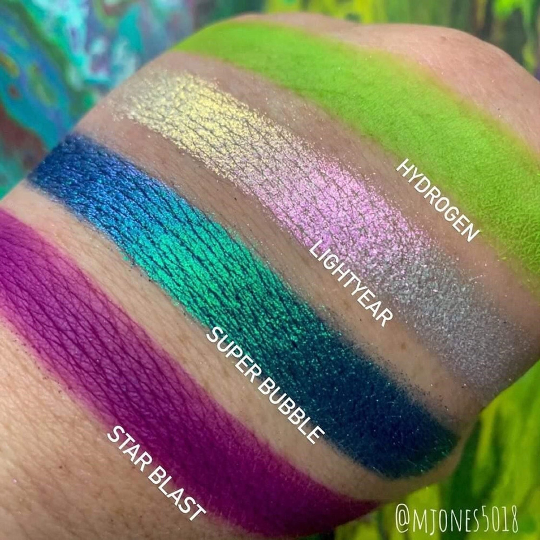 Close-up of shimmering teal and violet eyeshadows in the Cosmic Bubbles palette with textured surface details