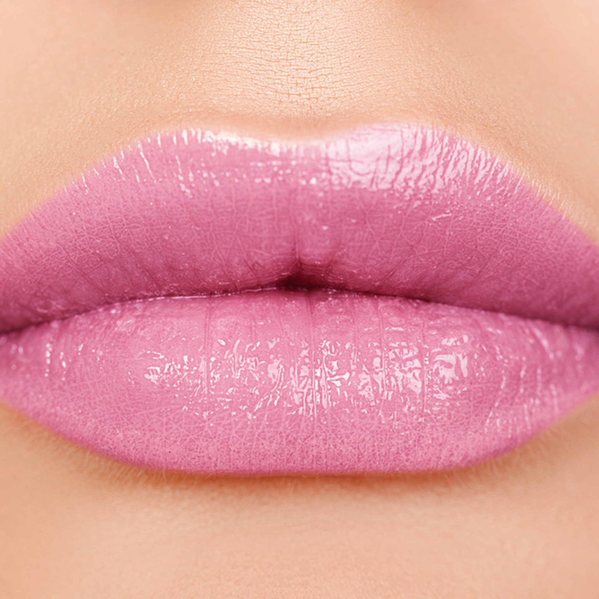 Lip gloss with pink color and glossy texture on lips