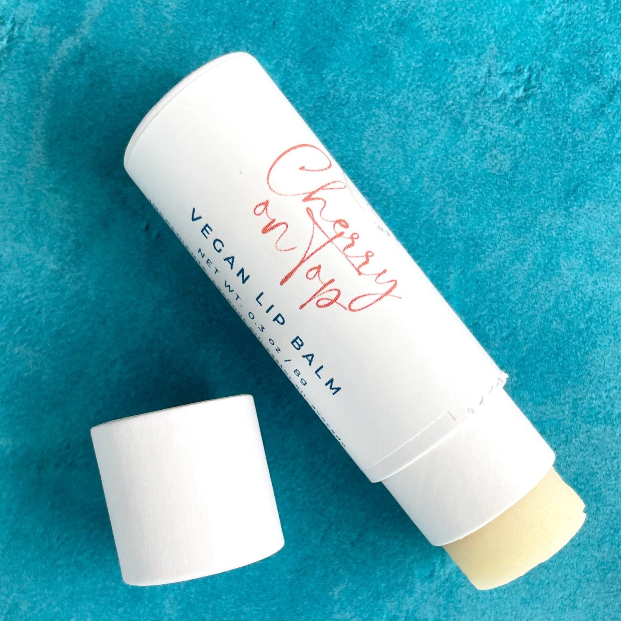 Lip balm in white tube with red script, exposed balm, and blue background.