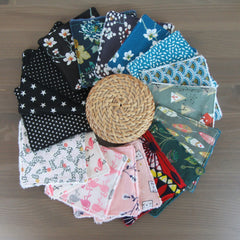 Stacked set of 7 bamboo fiber makeup remover wipes in assorted sizes with a sleek cotton pouch