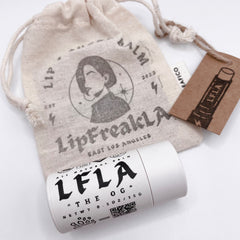 Lip balm tube with white and black text, beige canvas bag with printed design and brown tag with LFLA logo