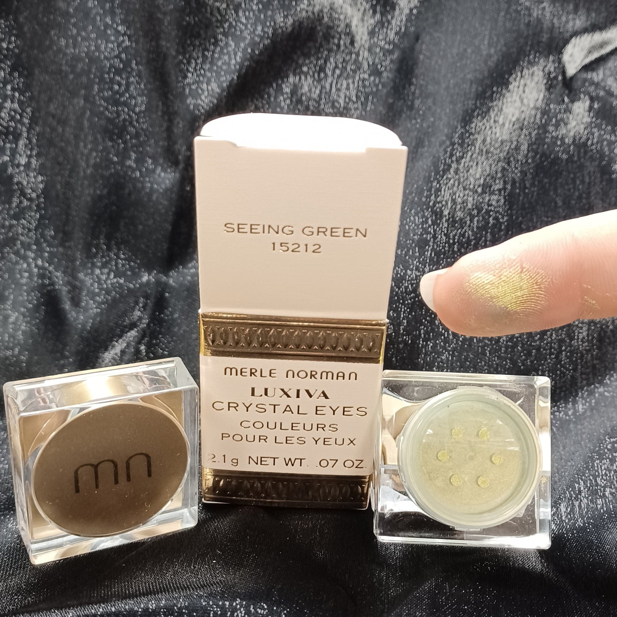 Side view of Merle Norman loose glitter eyeshadow jar showing sparkling powder texture and reflective particles