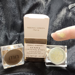 Side view of Merle Norman loose glitter eyeshadow jar showing sparkling powder texture and reflective particles