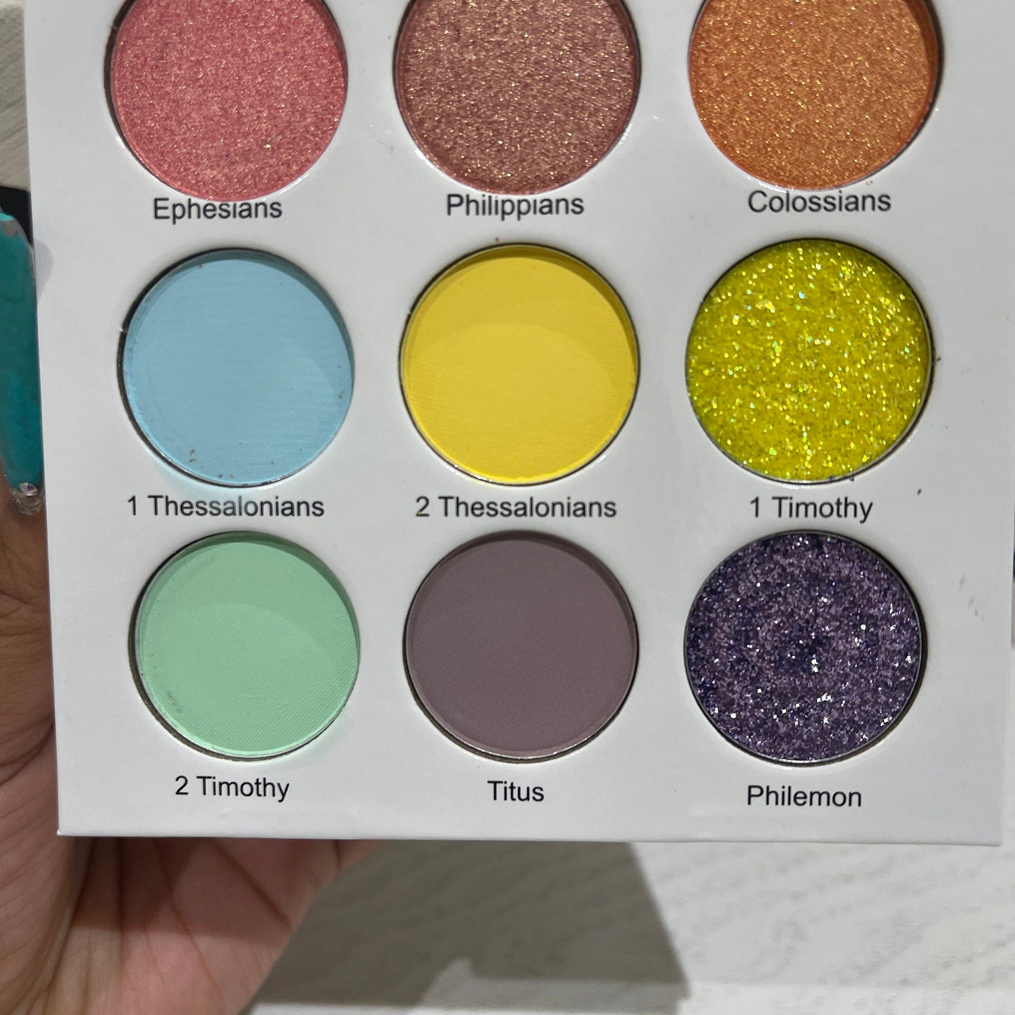 Close-up of vibrant teal and gold shimmer eyeshadows in the New Testament Edition palette with detailed texture.