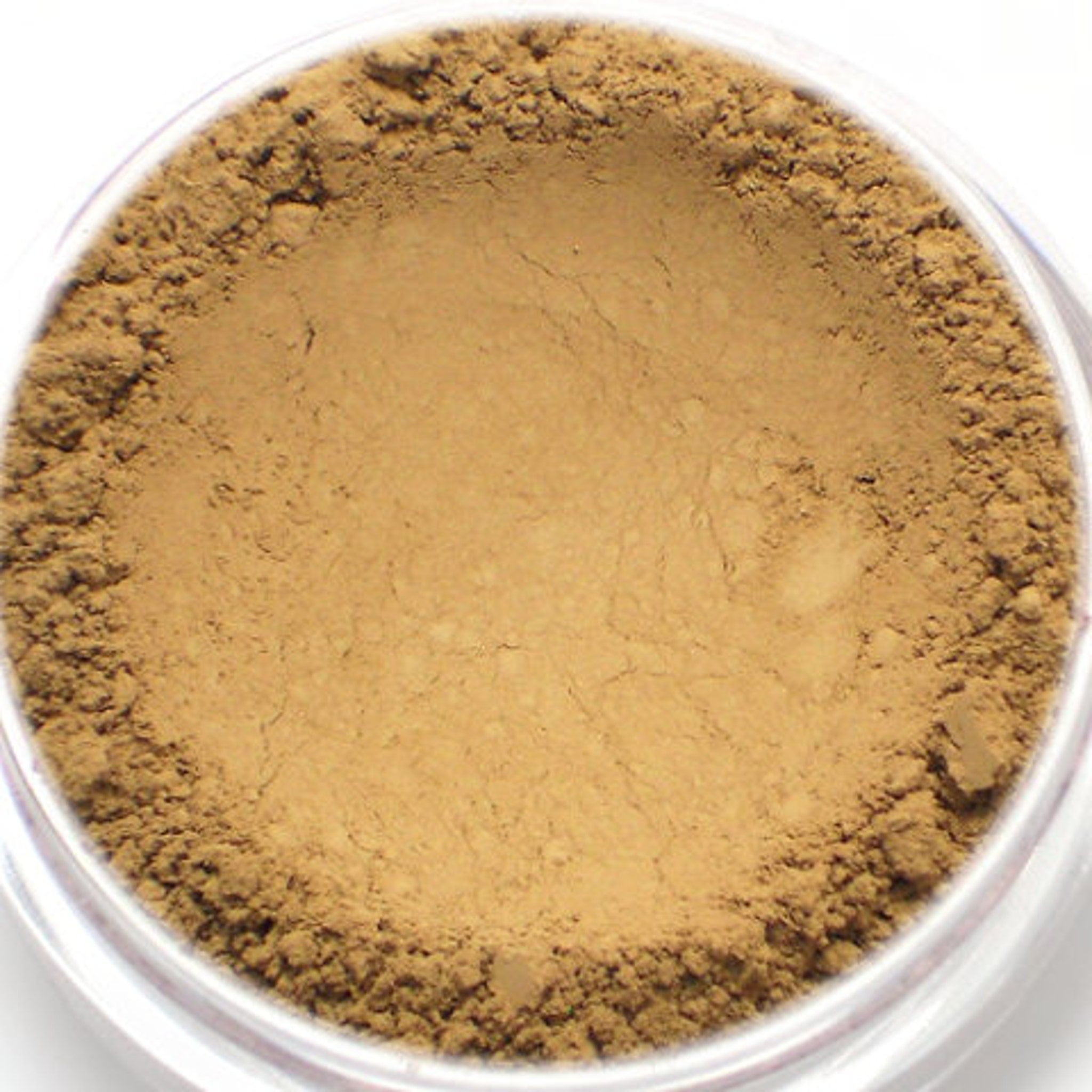 Powder makeup, tan powder with a rough texture, in a clear plastic container