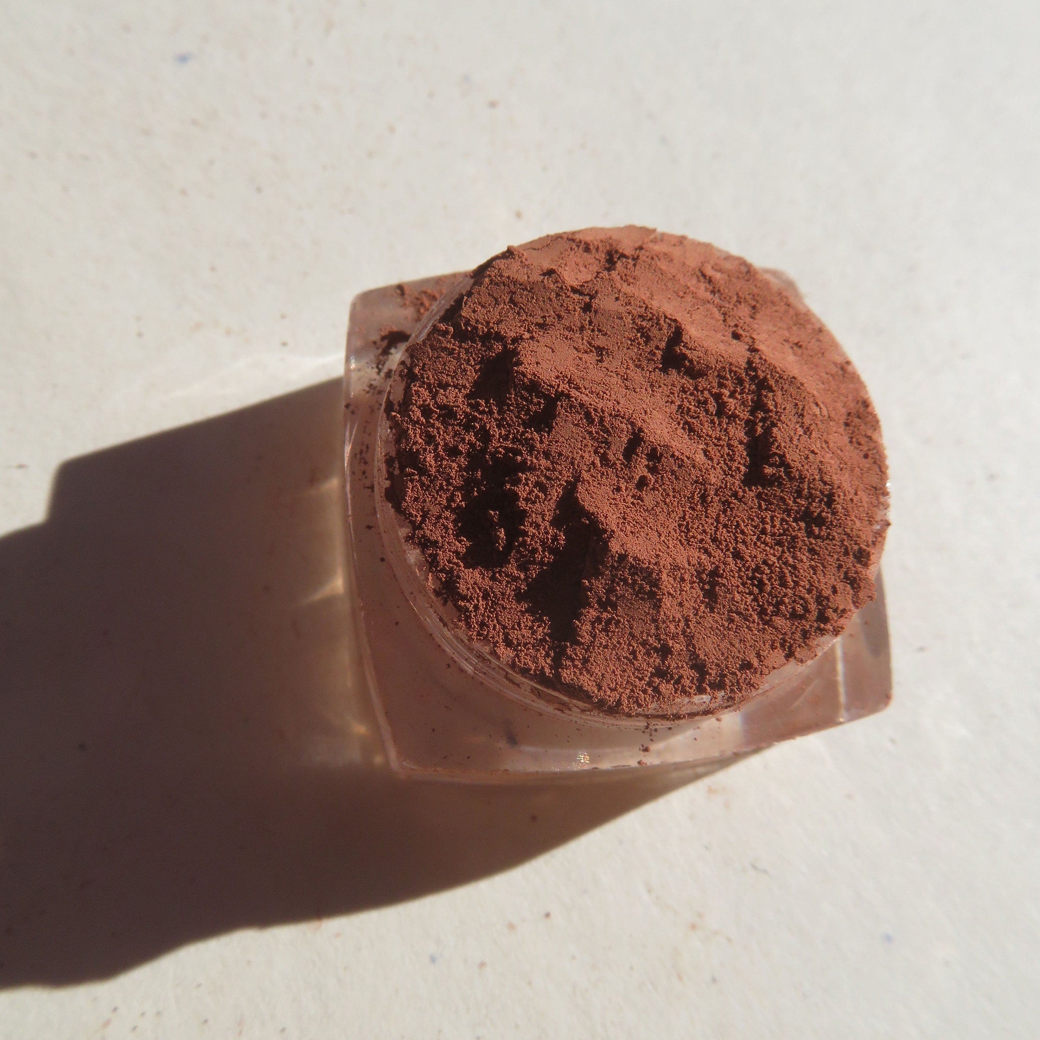 Side view of matte medium orange-brown mica mineral eye shadow in loose powder form, vegan and cruelty-free