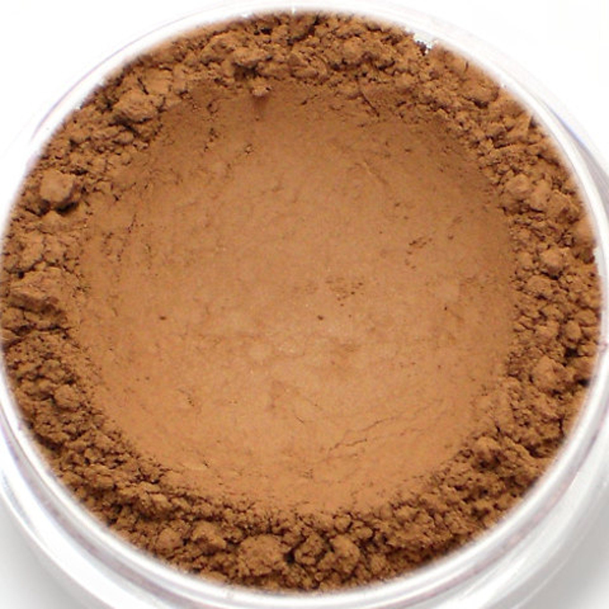 Powder makeup, brown, loose, granular texture, in clear container