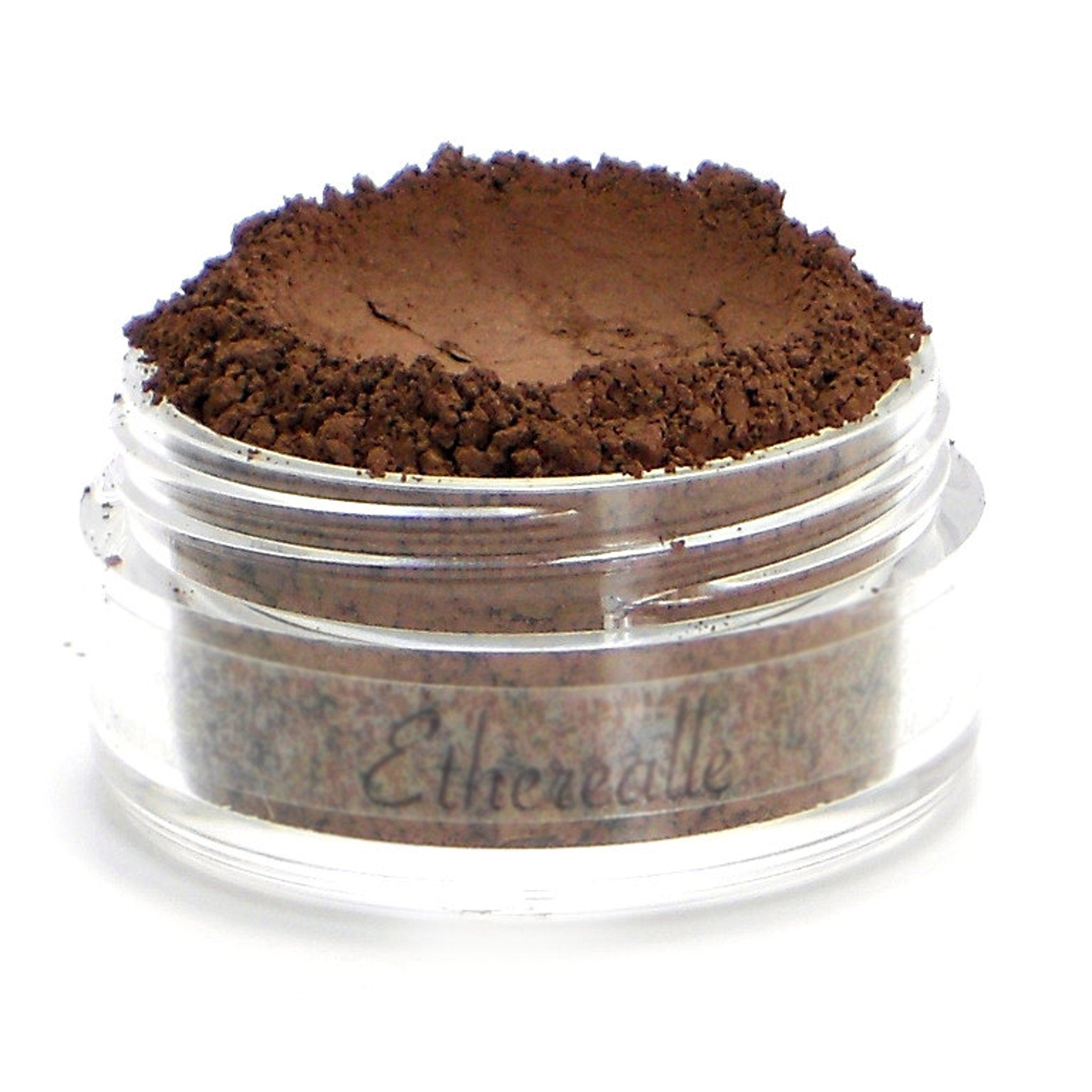 Brown powder makeup in clear jar with "Etherealle" text visible on the side