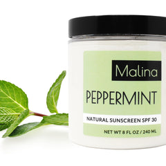 Natural sunscreen jar with black lid, white label, and green mint leaves, Malina New York