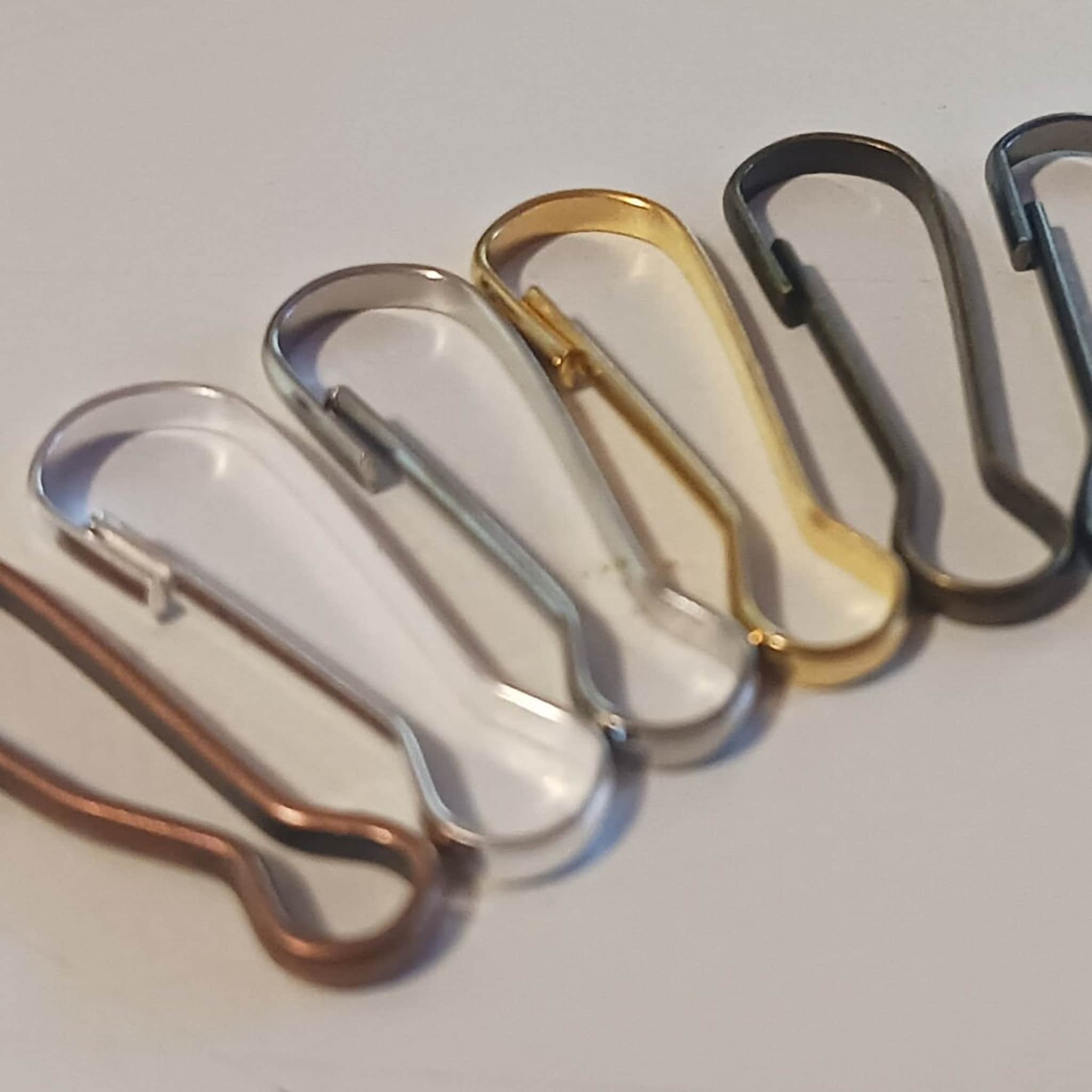 Metal safety pins in various colors, including silver, gold, and bronze, in a row