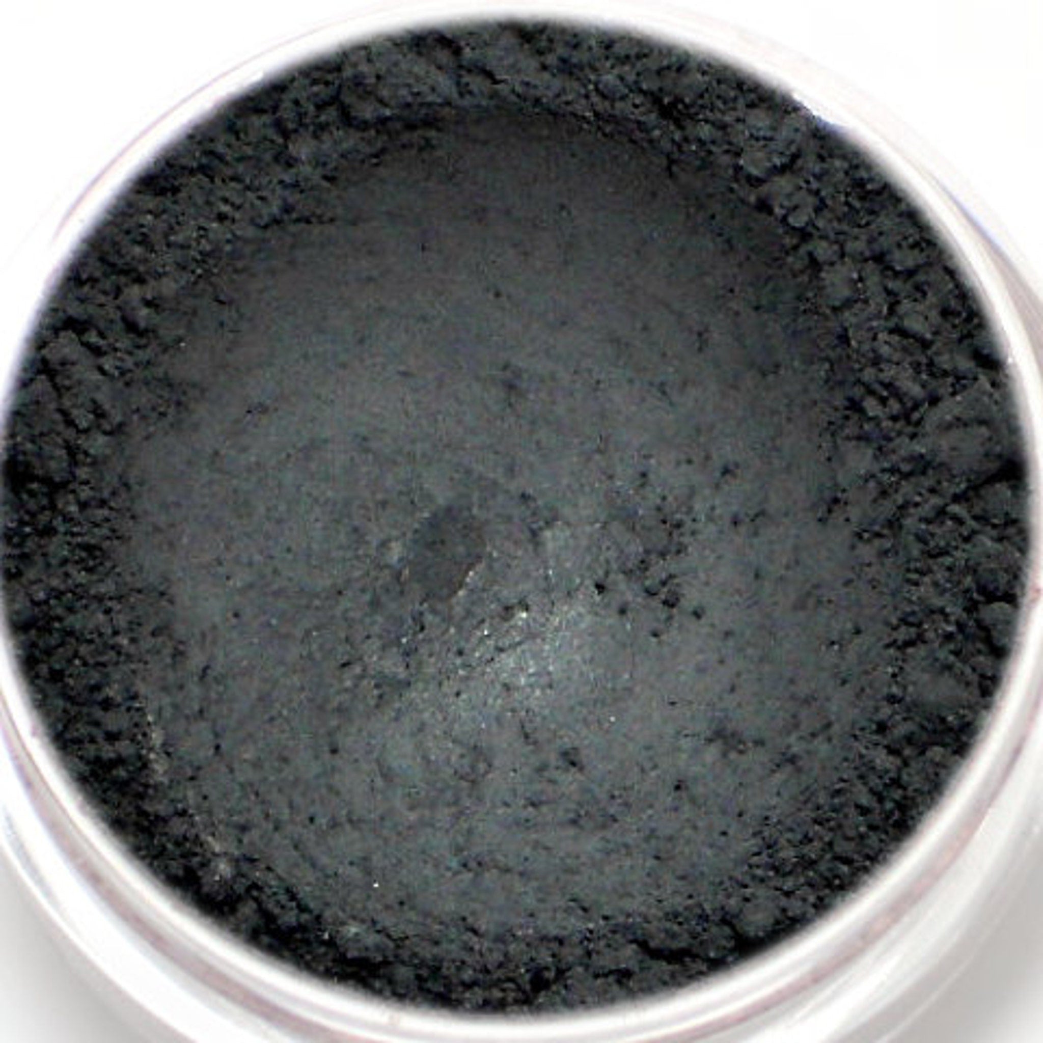 Matte black vegan eyeshadow in compact with Nero label, showcasing opaque mineral pigment texture.