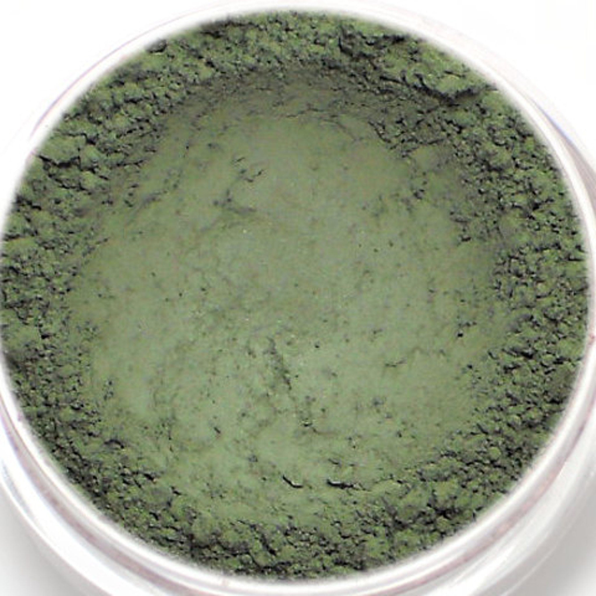 Matte khaki green eyeshadow pan in sleek black compact with silver logo, shown open on marble surface