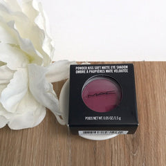 Eye shadow compact with MAC logo, dark pink color, in black box on white dish