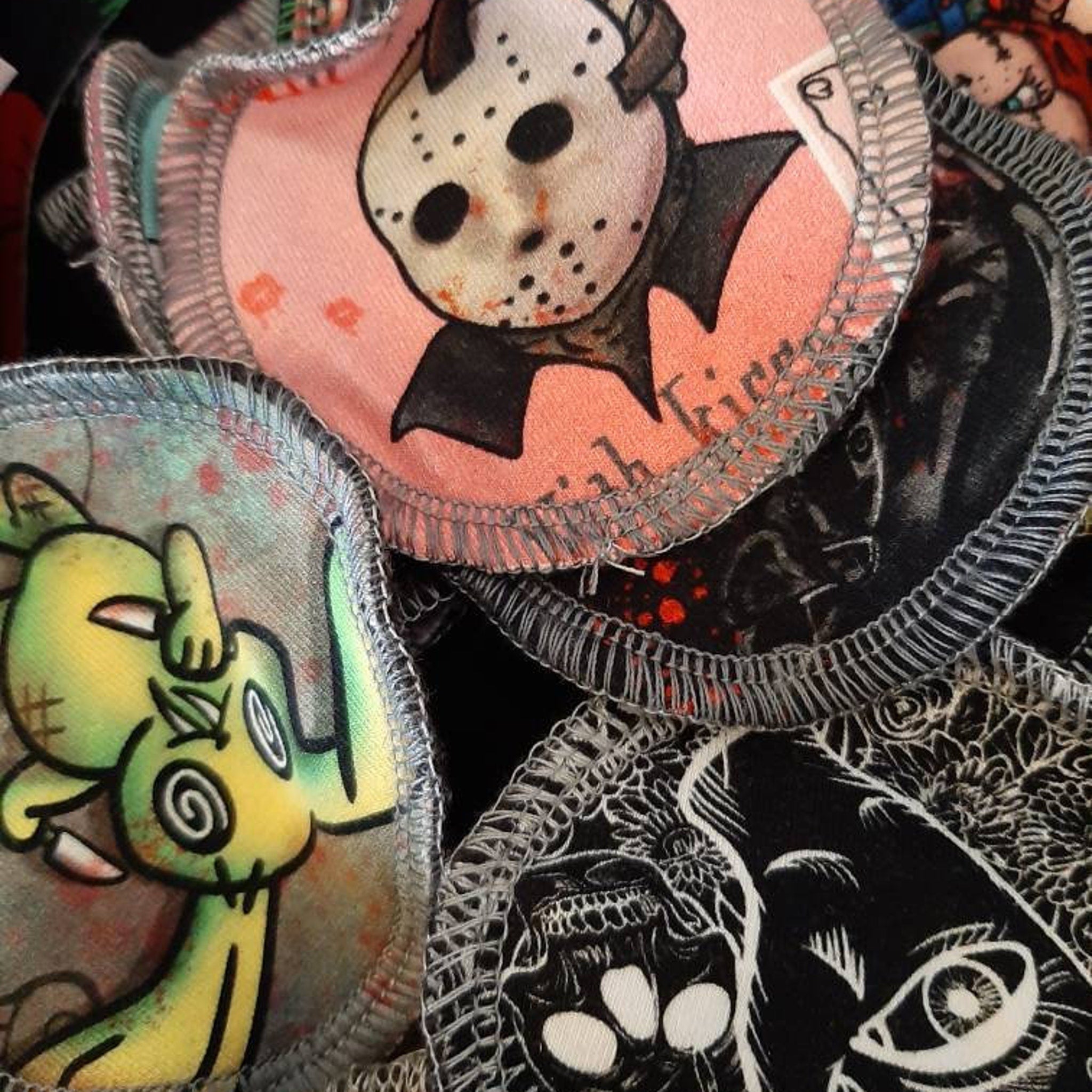 Round fabric patches with various horror-themed illustrations, pink, black, and green, with stitched edges