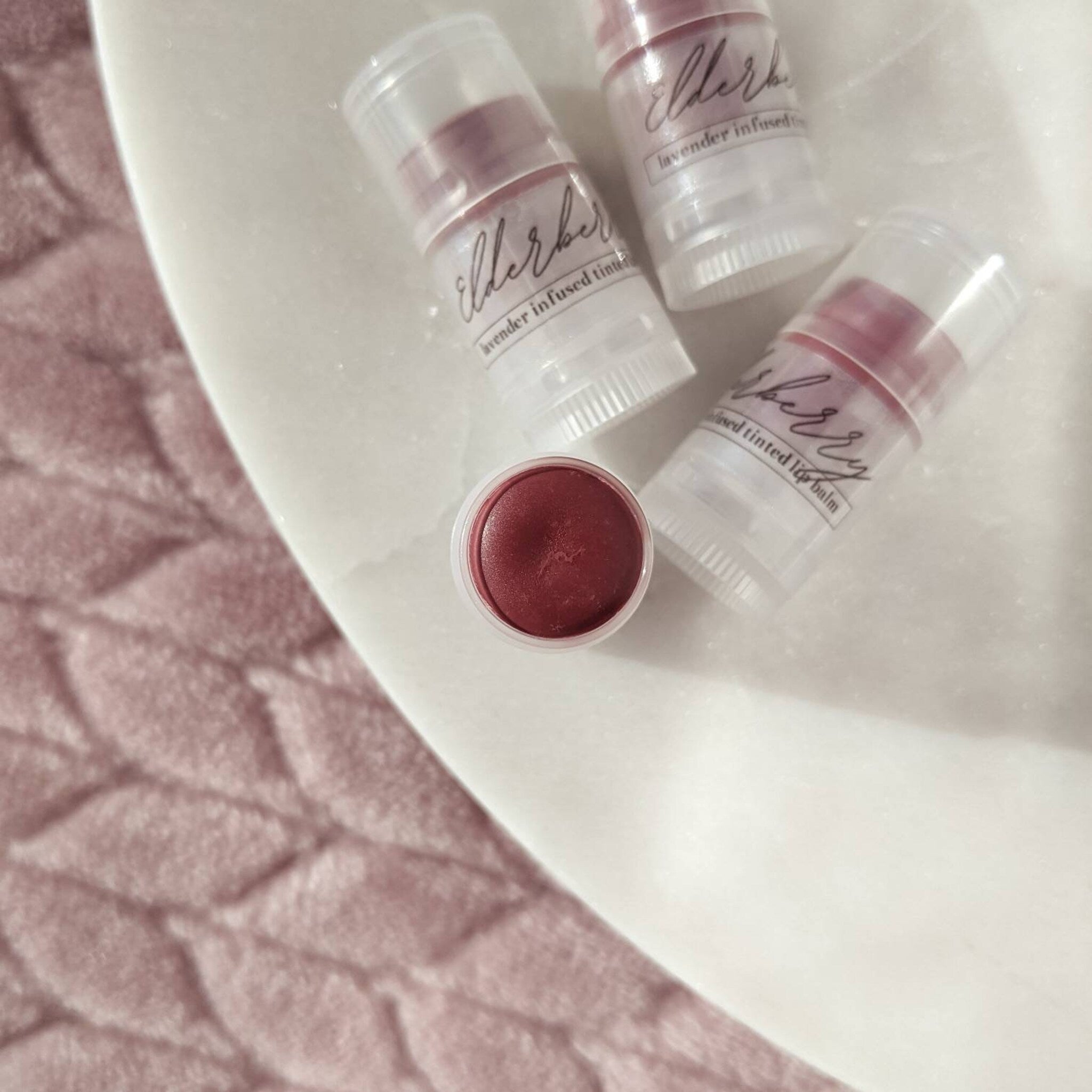 Lip balm, elderberry tinted, clear plastic tubes, BasswoodBeauty branding visible