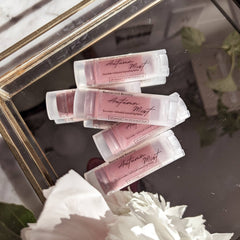 Lip balm tubes with pink tint and white plastic, Basswood Beauty brand name visible on label