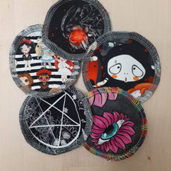 Reusable pads with black, white, and colorful patterns, featuring dolls, spider, and eye designs