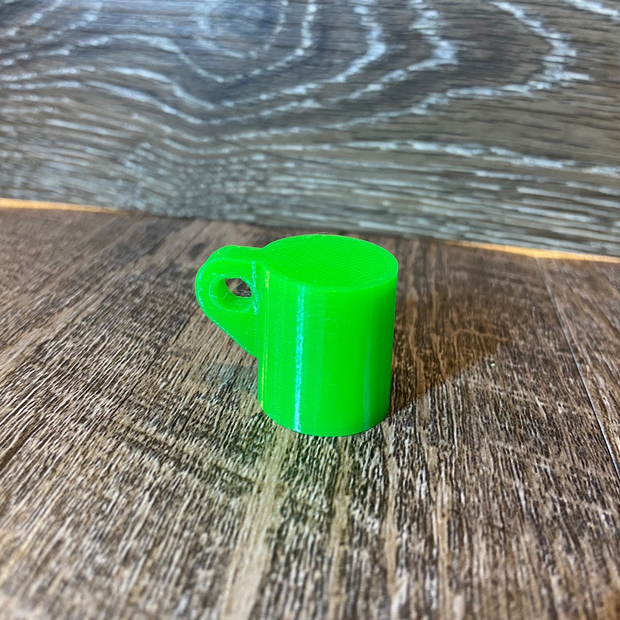 Green plastic mug with handle, on wood grain surface.