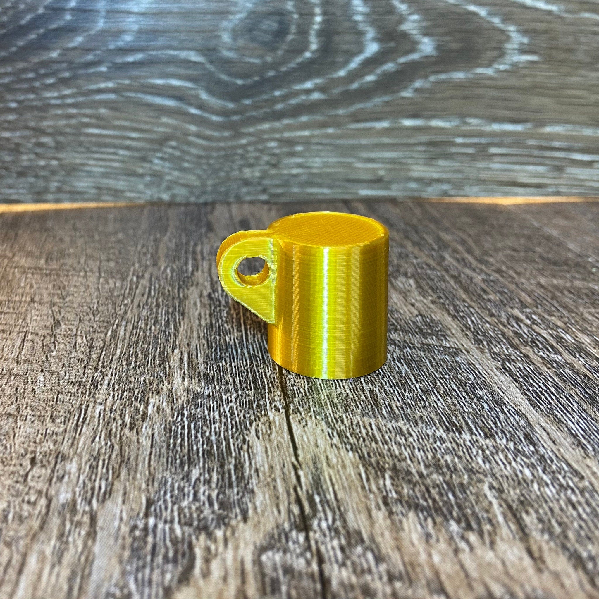 Yellow 3D printed mug with handle on wood grain surface