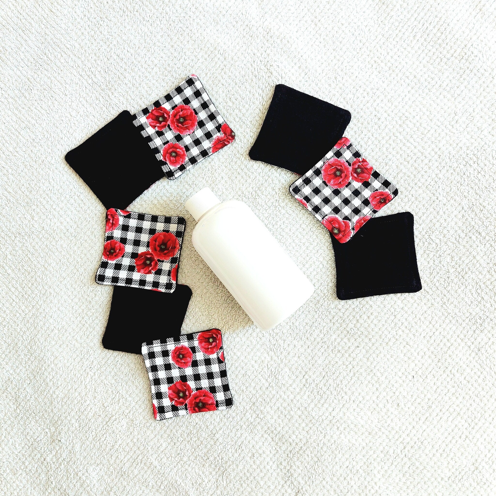 Makeup remover pads with black and floral plaid fabric, with a white bottle on white towel