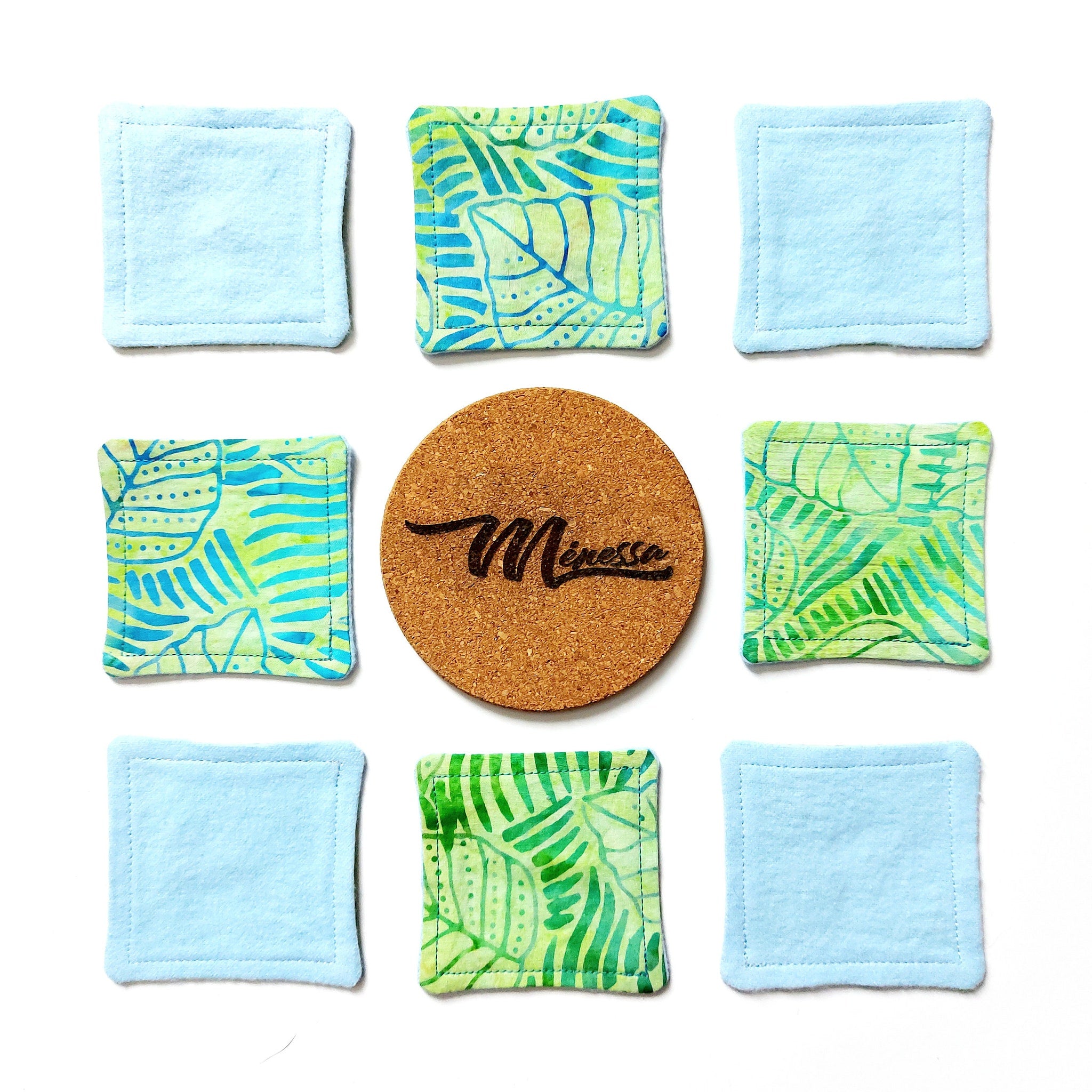 Reusable facial pads, blue, green, and patterned fabric, with Menessa logo on cork coaster