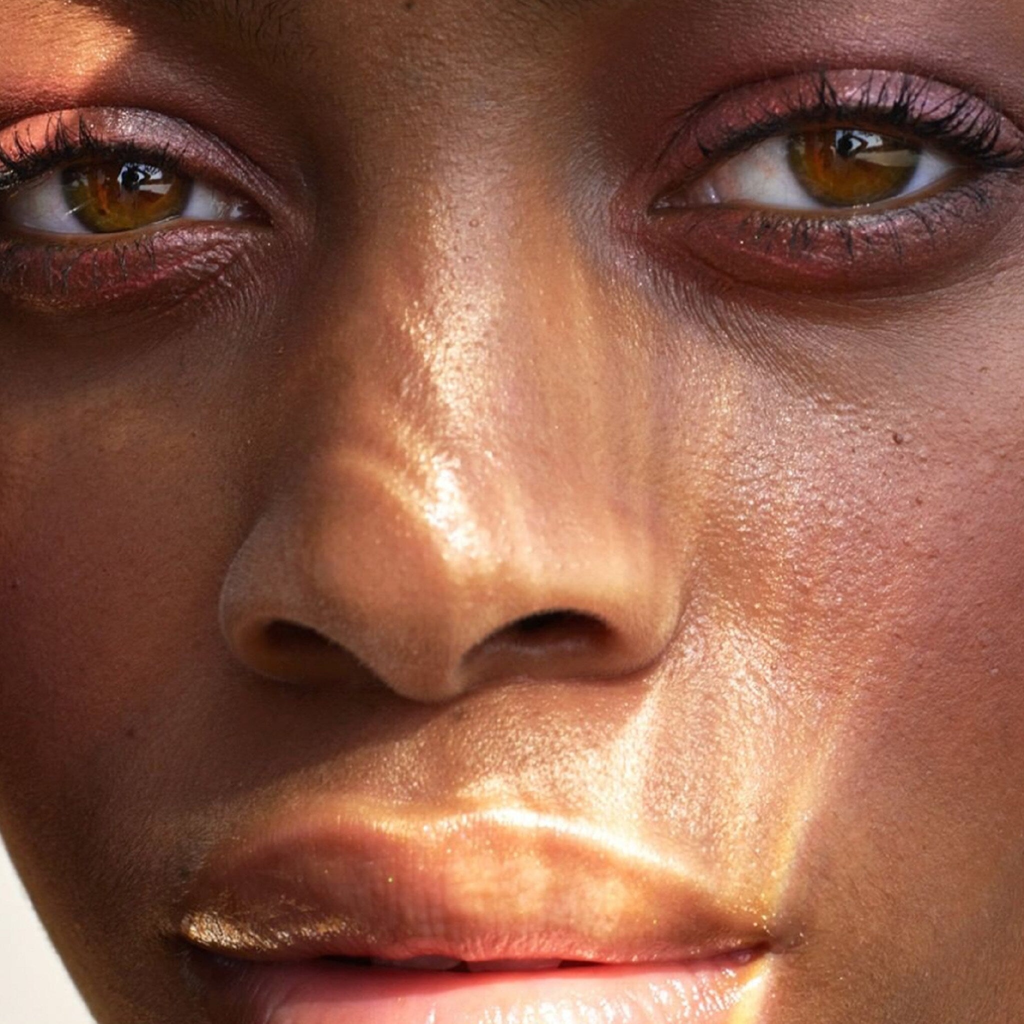 Makeup close-up with brown eyes, pink eyeshadow, and glowing skin in natural light