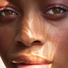 Makeup close-up with brown eyes, pink eyeshadow, and glowing skin in natural light