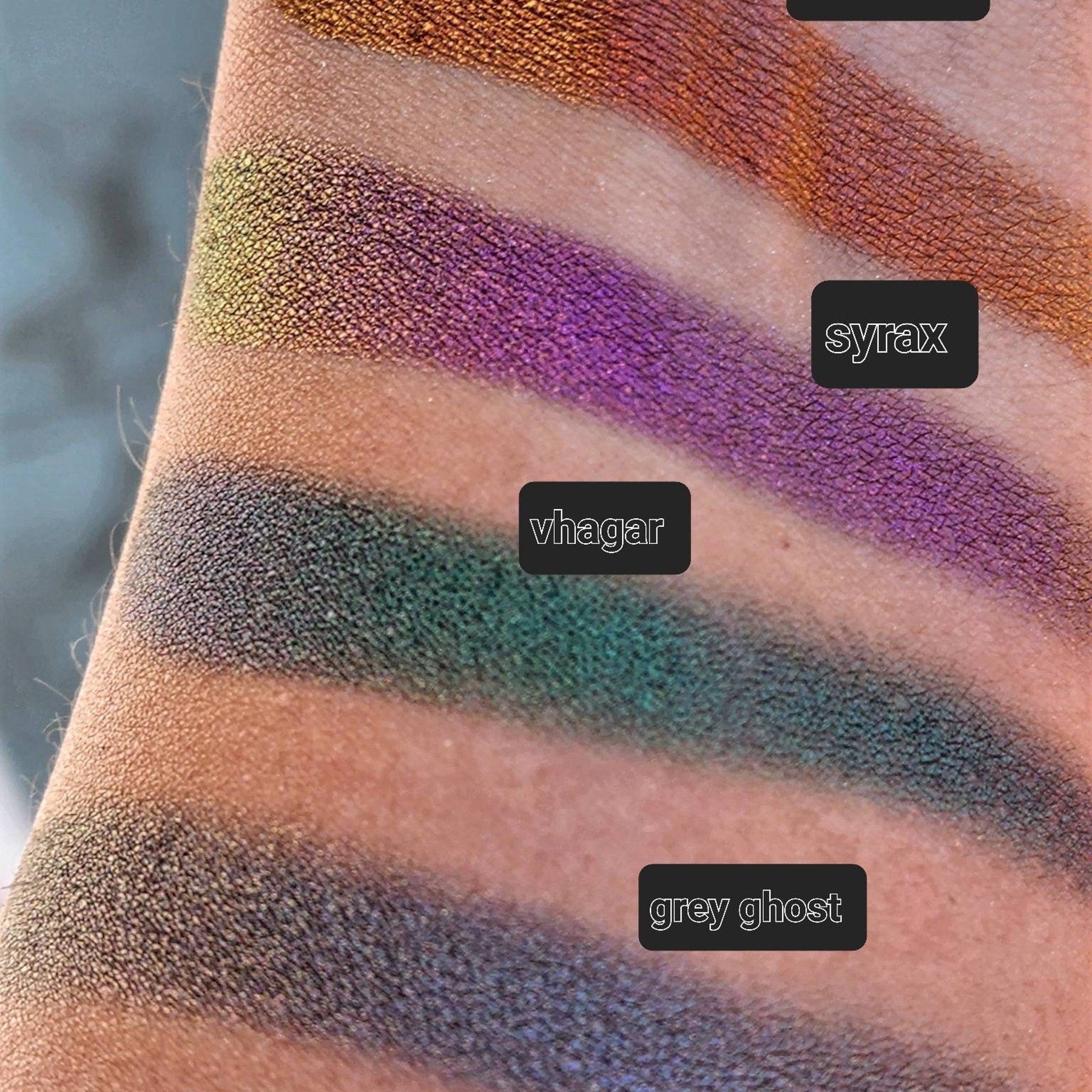 Eyeshadow swatches with metallic purple, green, and grey shades on skin, text labels "syrax", "vhagar", and "grey ghost