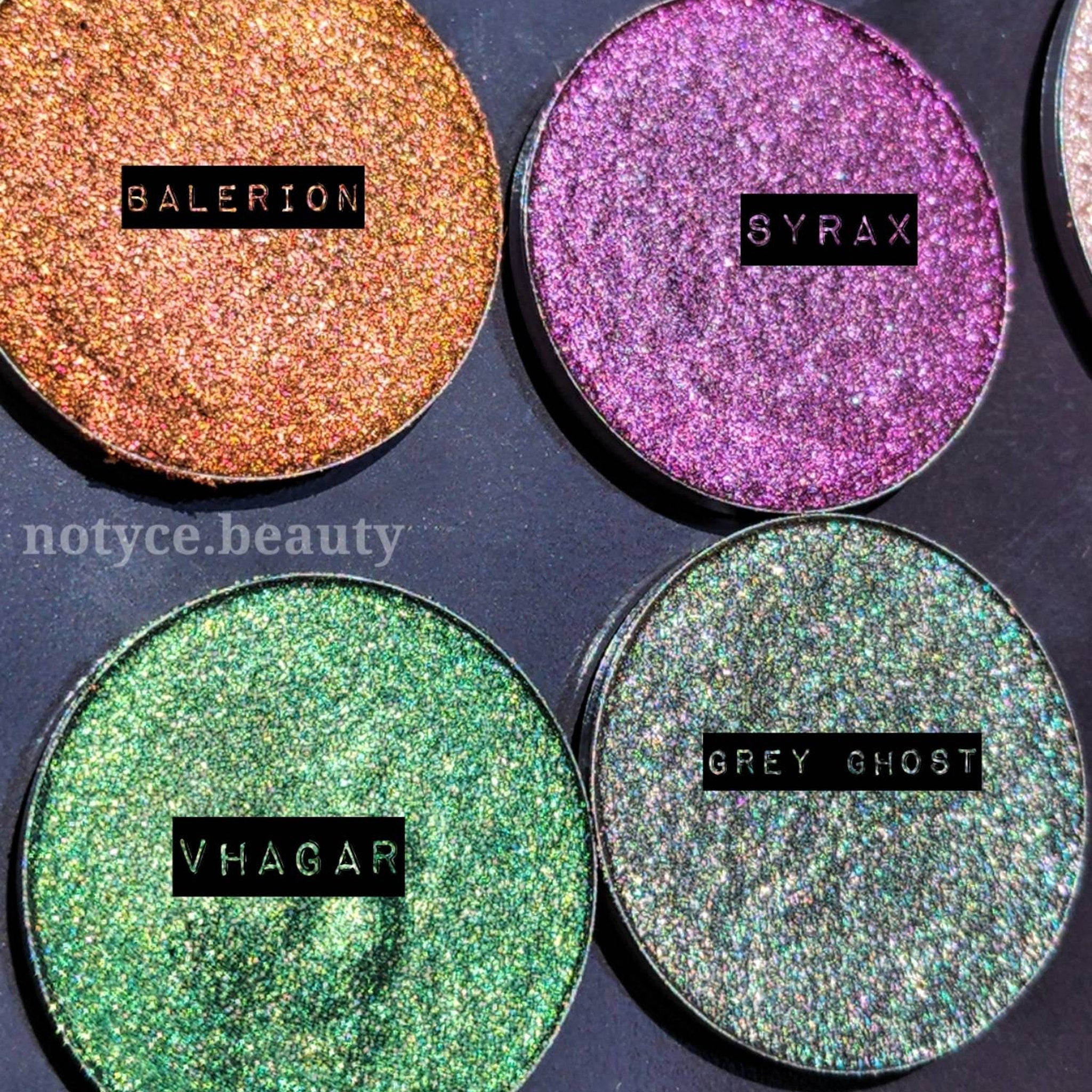 Eyeshadow palette with shimmery gold, purple, green, and grey shades, with text labels for each color