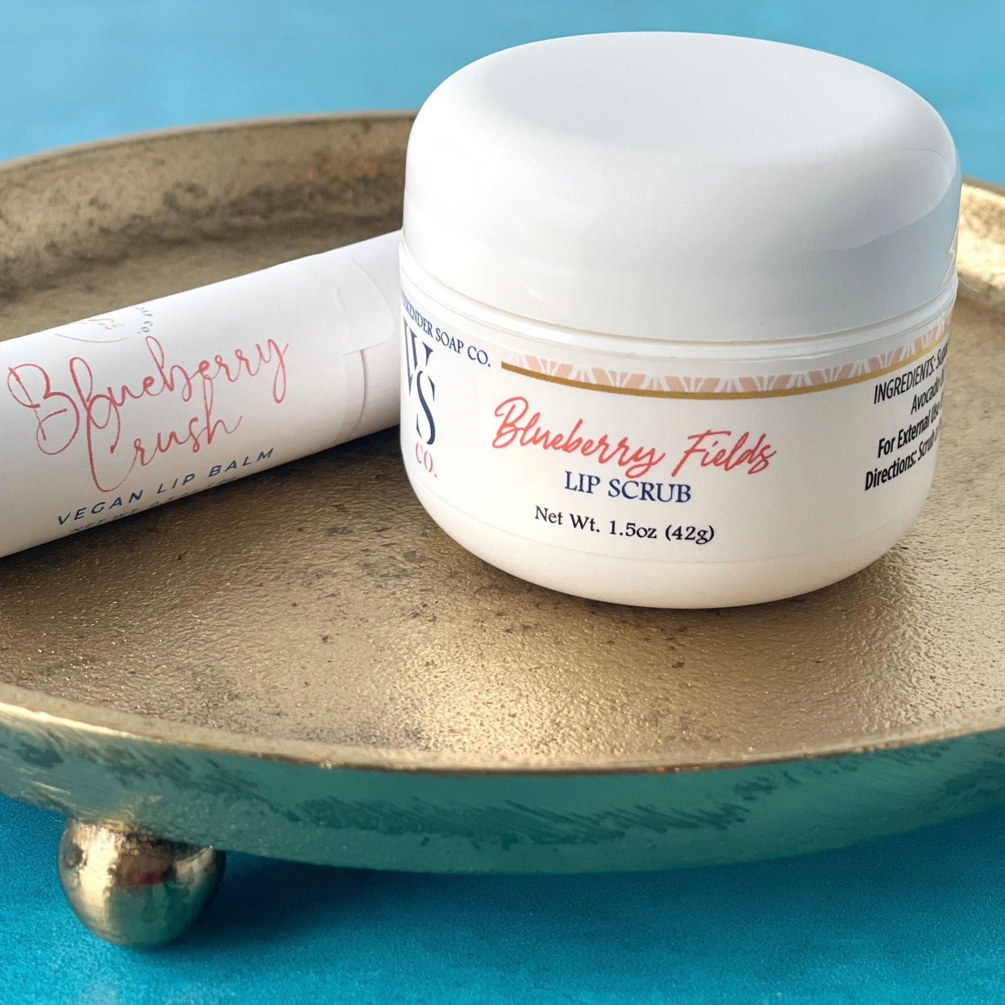 Lip scrub and lip balm set with white packaging, gold tray, and script text