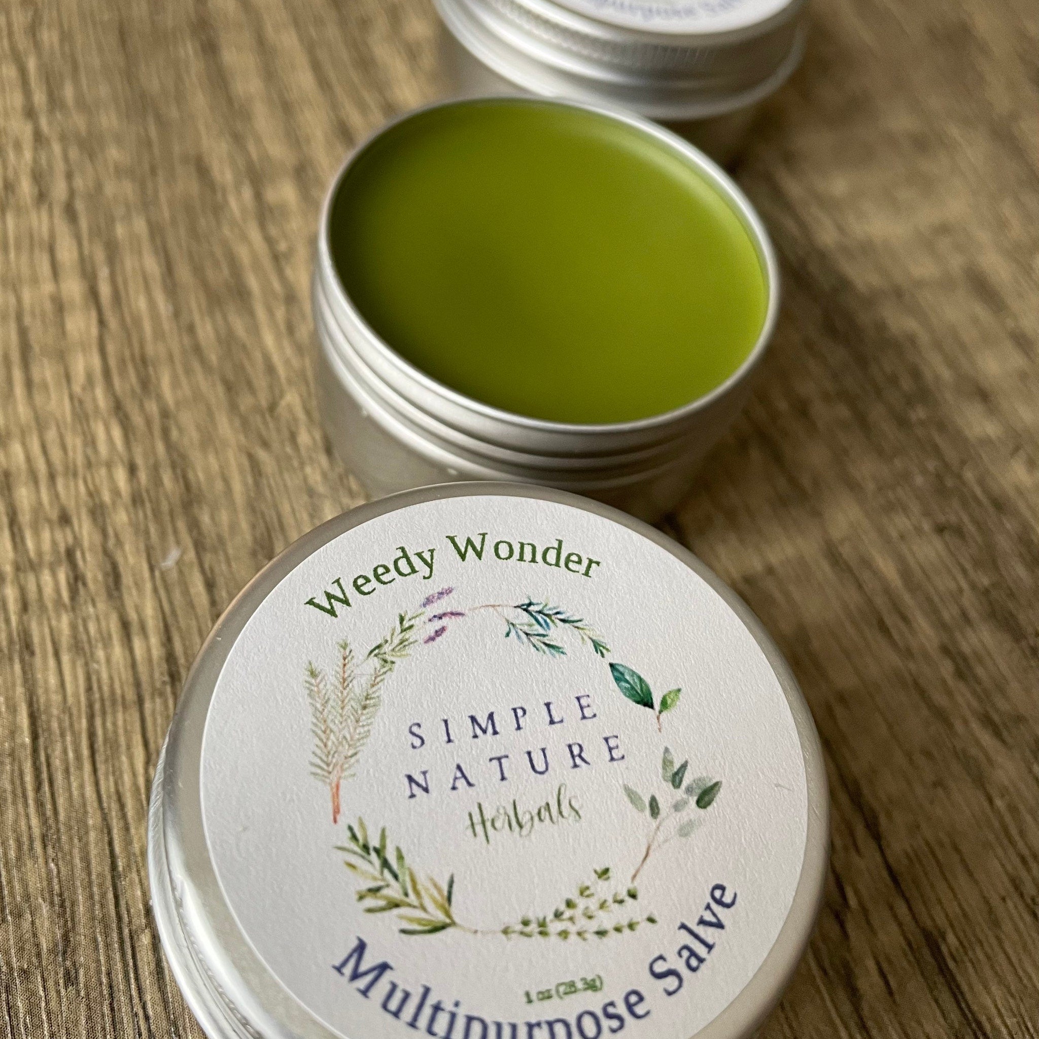 Multipurpose salve in silver tin with green balm, Simple Nature Herbals label on wood surface