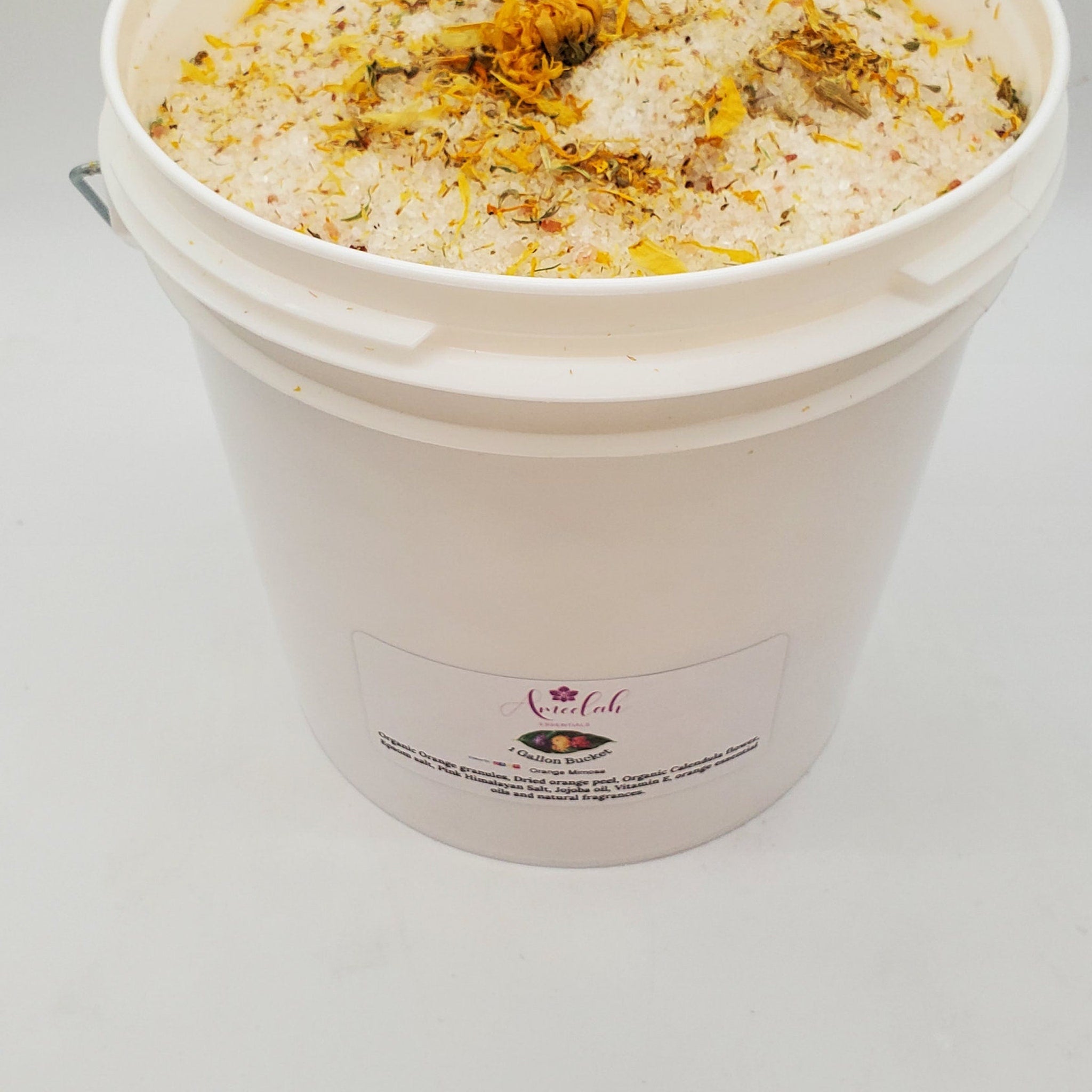Bath salt bucket with white container, orange and yellow botanicals, Ameelah Essentials label visible