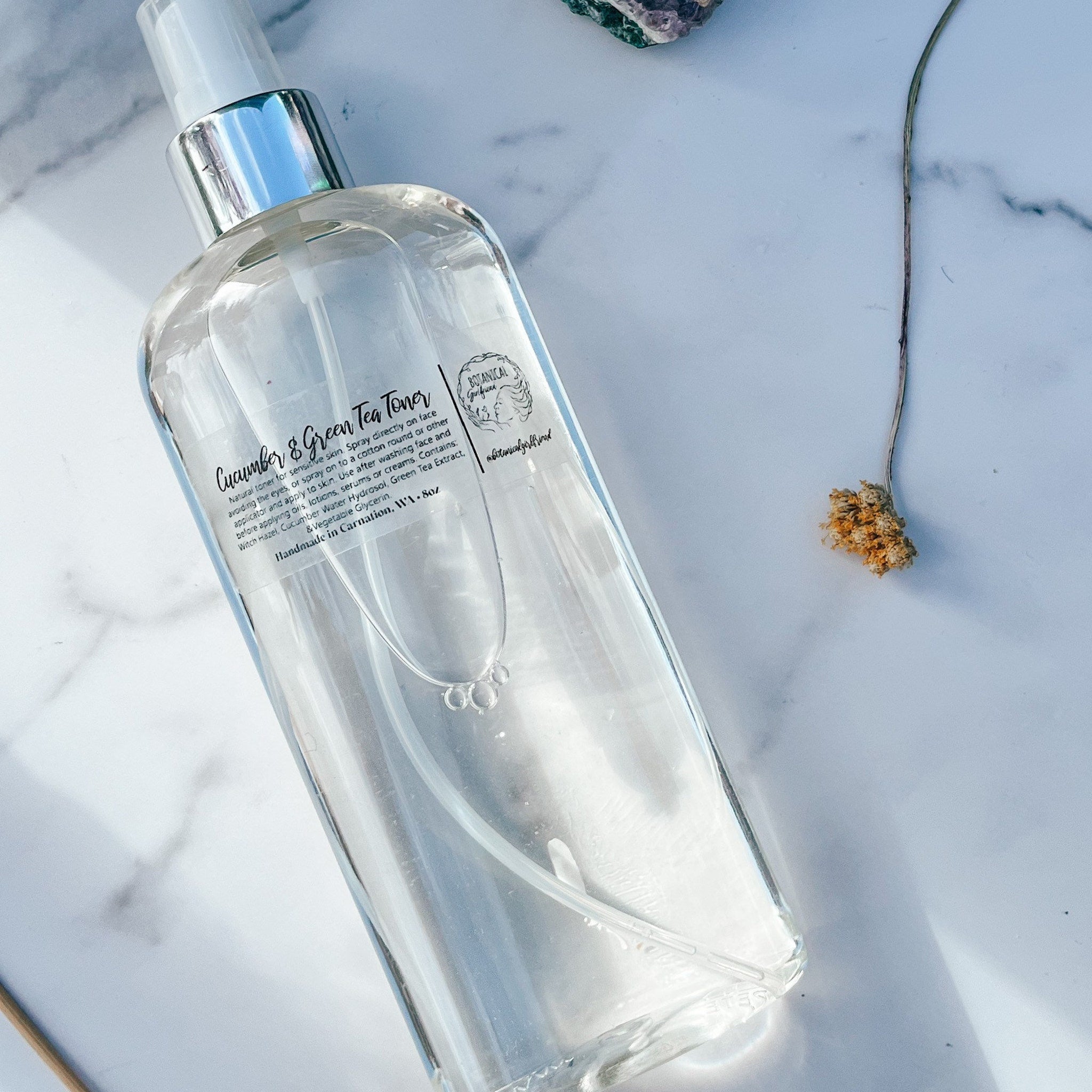 Toner bottle clear glass with silver sprayer and Botanical Girlfriend label on marble surface