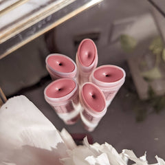 Lip balm tubes with pink color, plastic containers, and a reflective surface.
