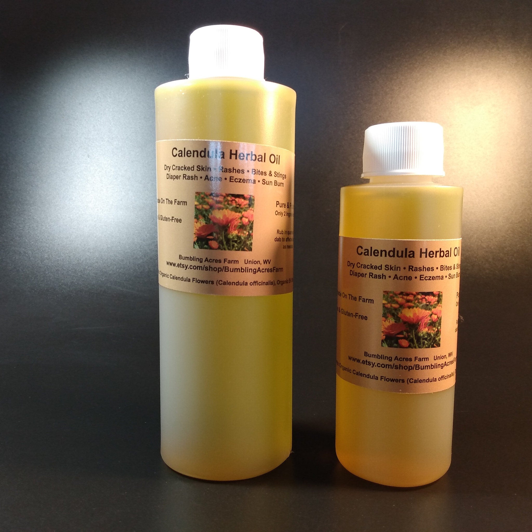 Calendula Herbal Oil bottles with yellow liquid, white caps, and tan labels, Bumbling Acres Farm