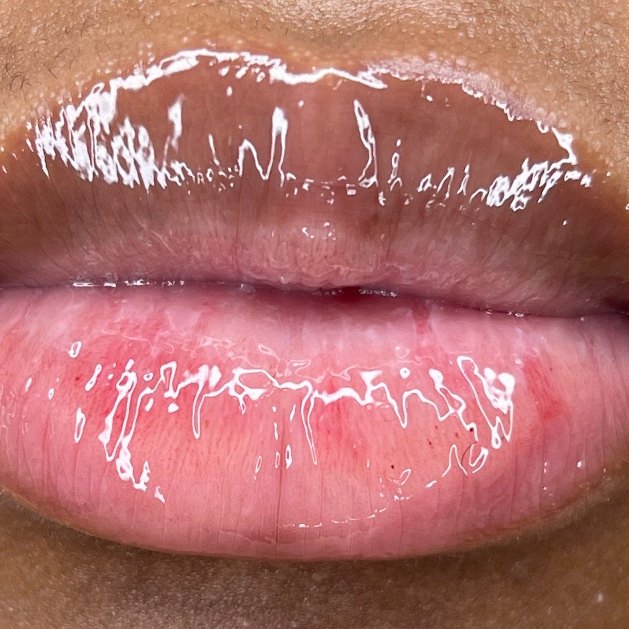 Lip gloss, glossy pink and brown lips, close-up view of a person's mouth.