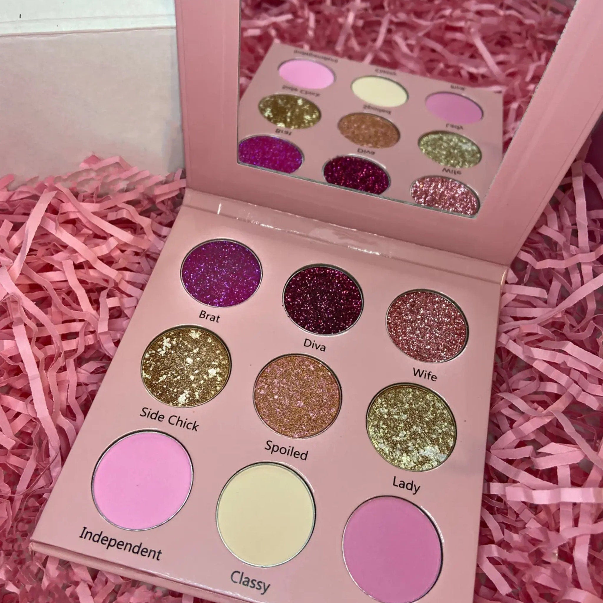 Close-up of Bratty Doll Eye Shadow Palette showing 12 vibrant matte and shimmer shades in a sleek black compact