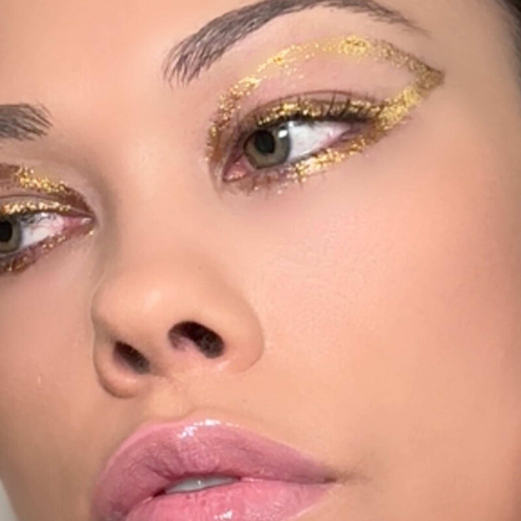 Gold glitter gel pot with aloe vera, shown swatched on hand for vegan makeup shimmer effect