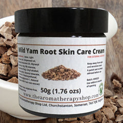 White tube of wild yam root cream with green herbal accents and matte finish, resting on wooden surface