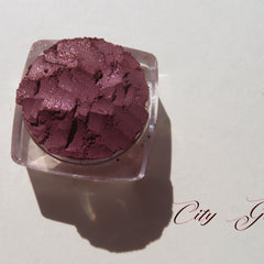 Loose vegan mineral eye shadow in dark mauve with shimmering pink sheen, cruelty-free, displayed in open jar.