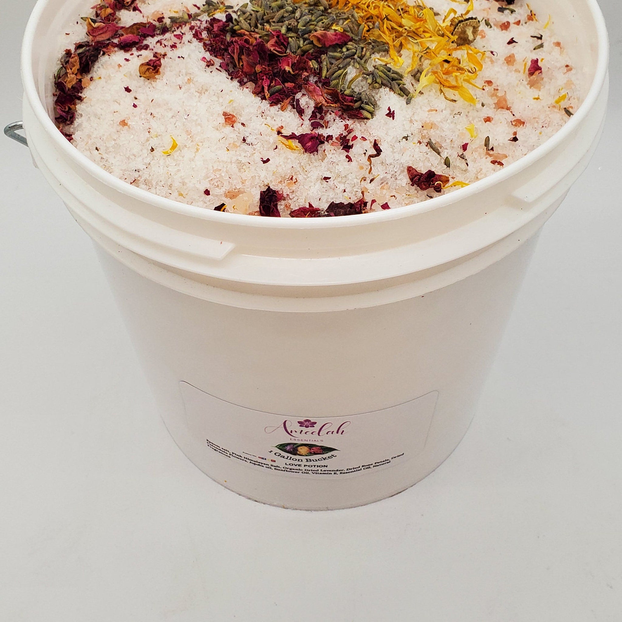 Bath salts with white crystals, dried flowers, and Ameelah Essentials label on bucket