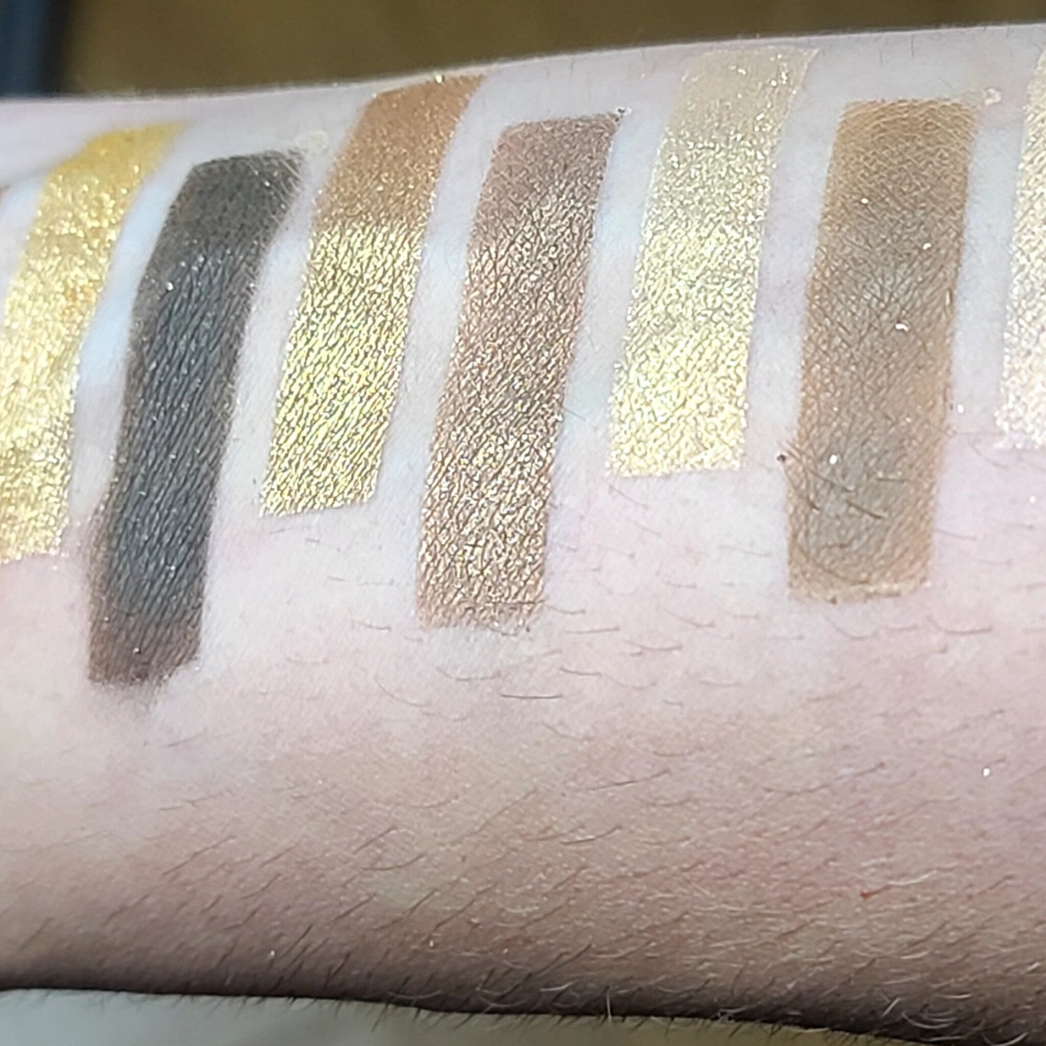 Close-up of 12 vibrant eyeshadow pans in matte and shimmer finishes, arranged in a sleek black palette