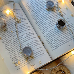 Open book with string lights, small jars of powder, and dried flowers on page