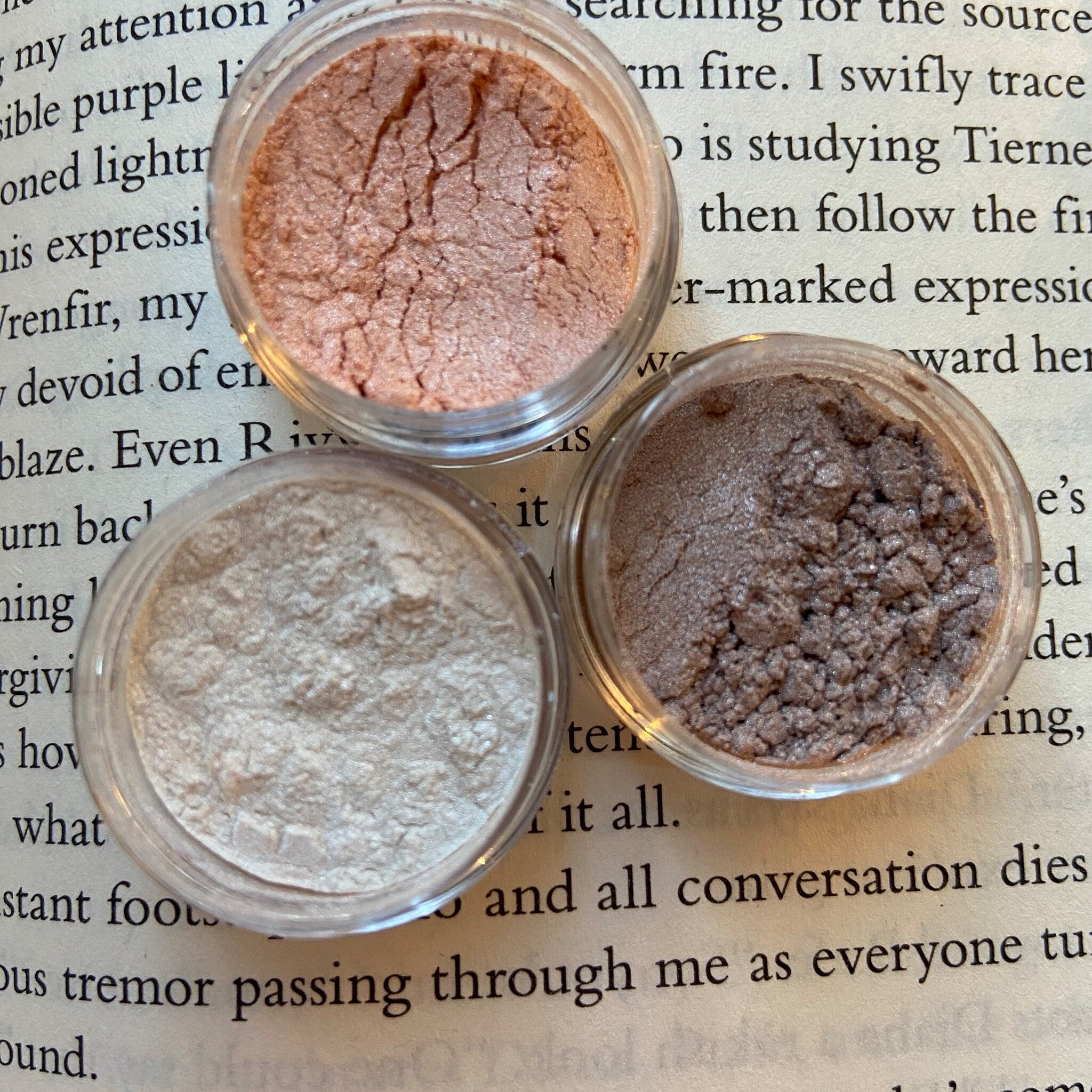 Close-up of a hand applying shimmery taupe eye shadow with a fluffy brush for a blended look