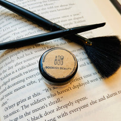 Makeup brushes black bristles and handles with Bookish Beauty jar on book page